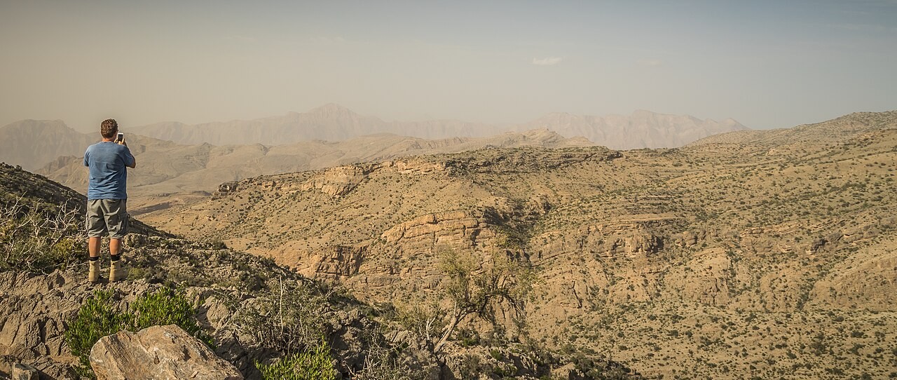 Wanderer blickt über die felsige Berglandschaft des Jabal Akhdar